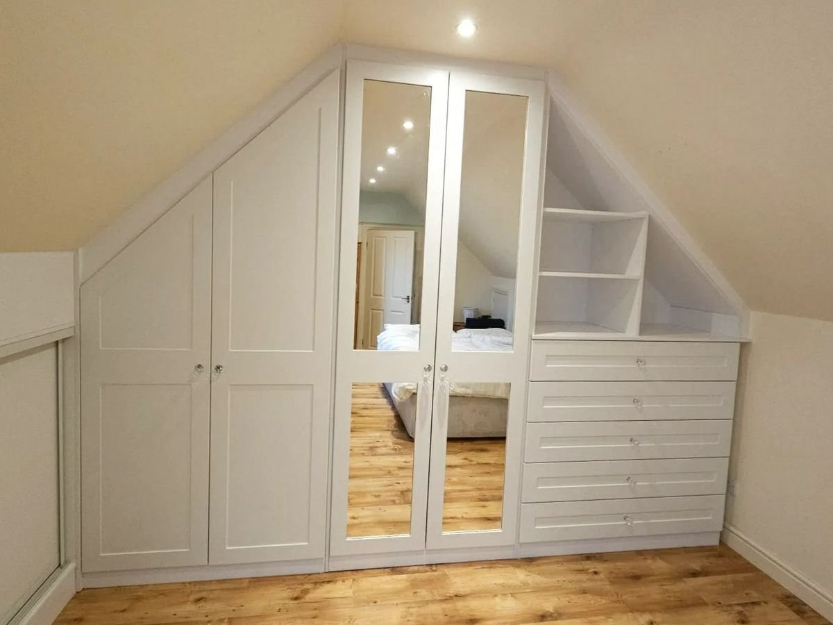 Loft bedroom with mirrored and shaker wardrobes and drawers built under a sloping ceiling