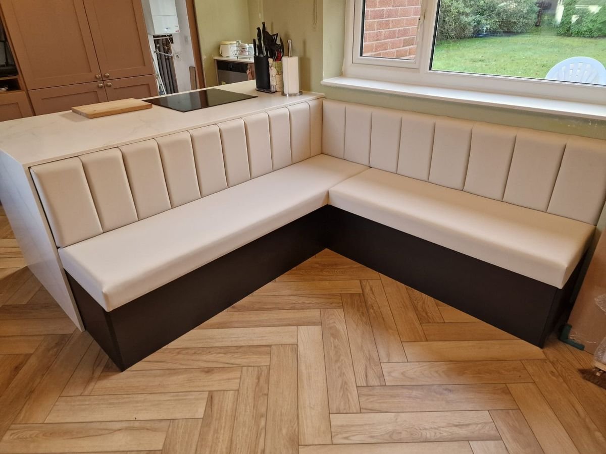 Built-in L-shaped kitchen banquette seating with panelled backs below a window