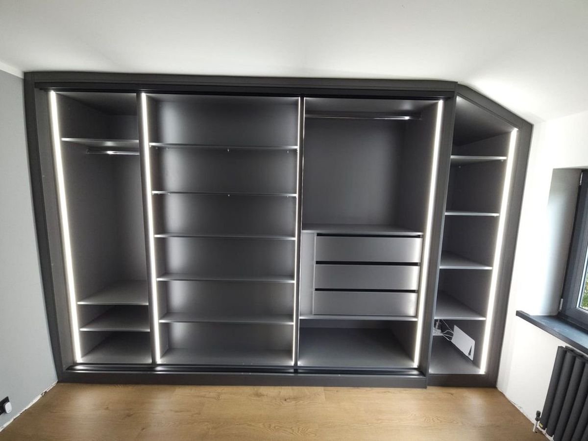 LED strip lighting inside a dark grey fitted wardrobe with shelves and drawers