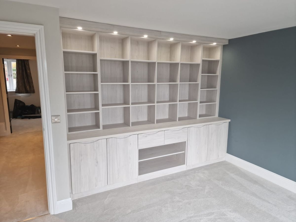 Fitted study wall with lit open shelving above low cupboards