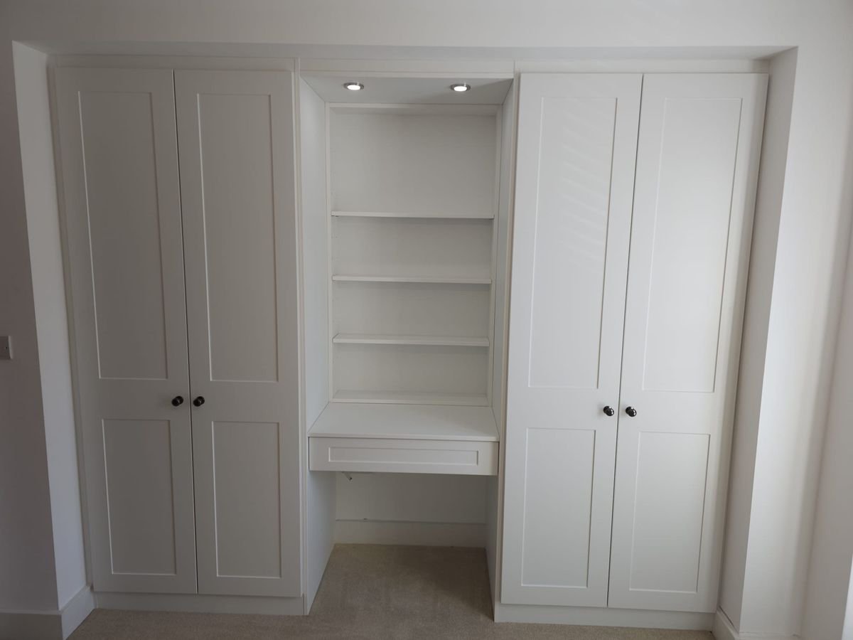 White shaker fitted wardrobes either side of a lit dressing niche with open shelves