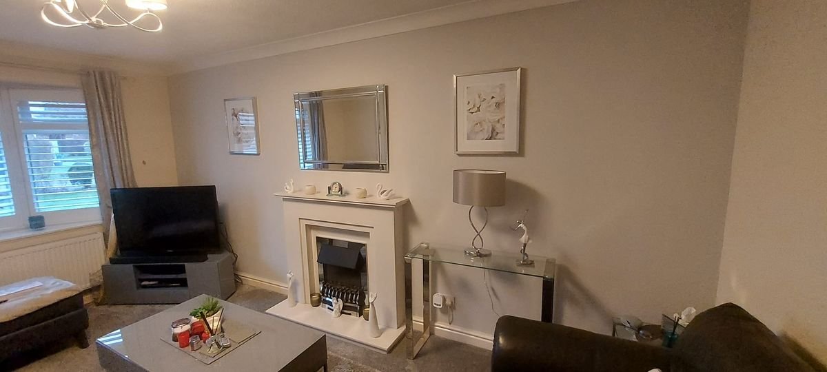 Living room before the media wall, with a TV on a stand beside a fireplace Living room before the media wall, with a TV on a stand beside a fireplace