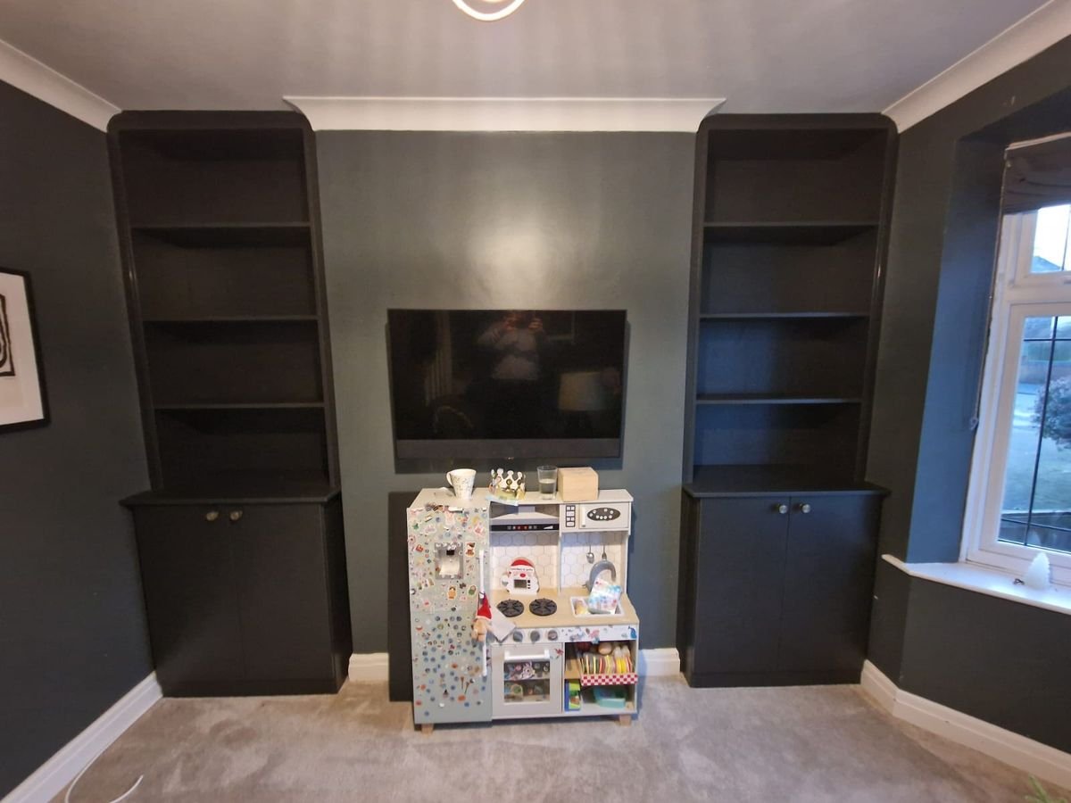 Dark painted alcove cupboards and shelving either side of a wall-mounted TV Dark painted alcove cupboards and shelving either side of a wall-mounted TV