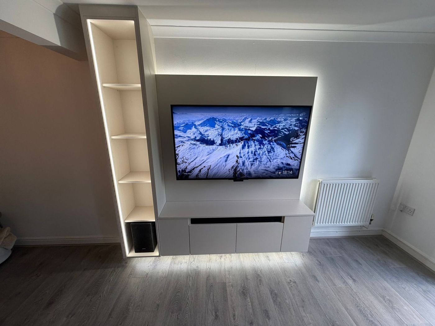 Floating media wall panel with a backlit TV, a tall lit shelf and a low storage unit Floating media wall panel with a backlit TV, a tall lit shelf and a low storage unit