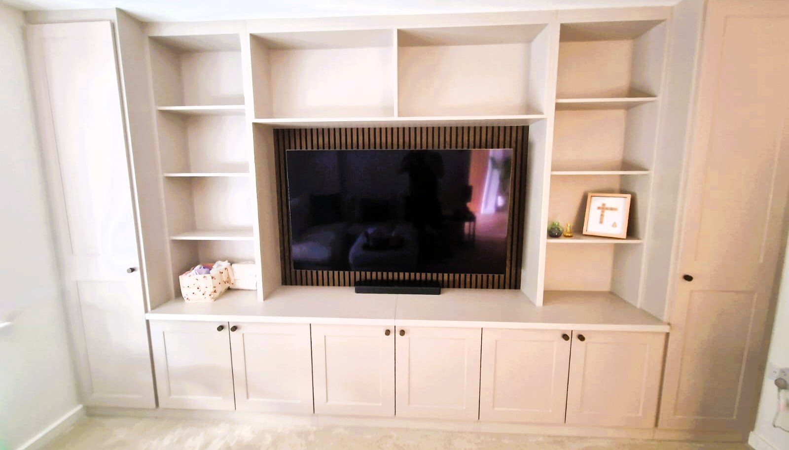 A bespoke media wall / entertainment unit with shelving, cupboards and tall storage. Cable management built in.